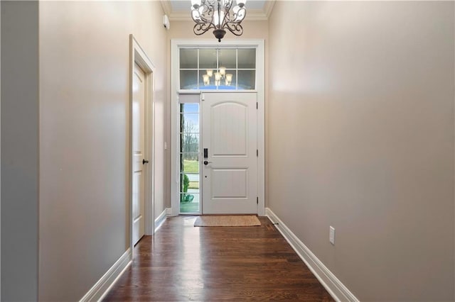 foyer entrance with ornamental molding, baseboards, a chandelier, and dark wood-type flooring