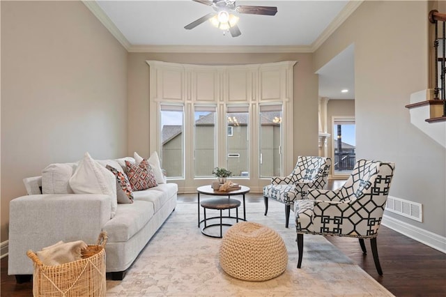 living area featuring crown molding, visible vents, ceiling fan, baseboards, and wood finished floors