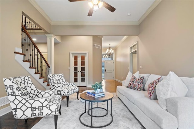 living area featuring visible vents, baseboards, ornamental molding, wood finished floors, and ceiling fan with notable chandelier
