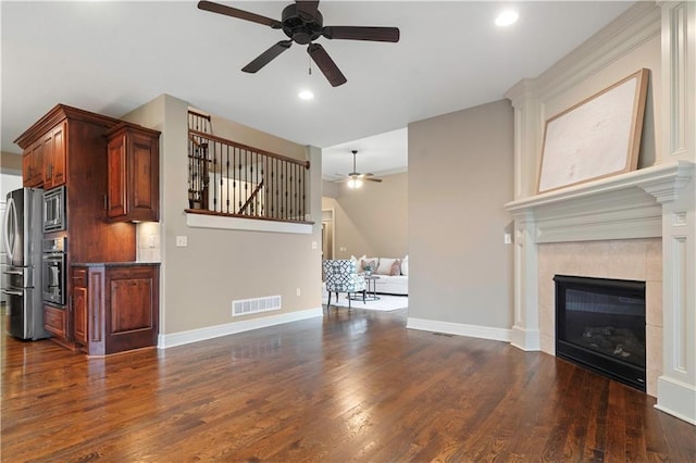 unfurnished living room with baseboards, dark wood-style flooring, recessed lighting, a tiled fireplace, and a ceiling fan