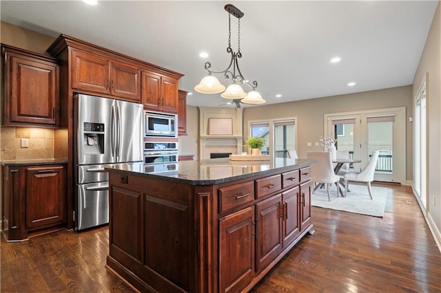 kitchen featuring dark stone countertops, stainless steel appliances, recessed lighting, dark wood finished floors, and backsplash