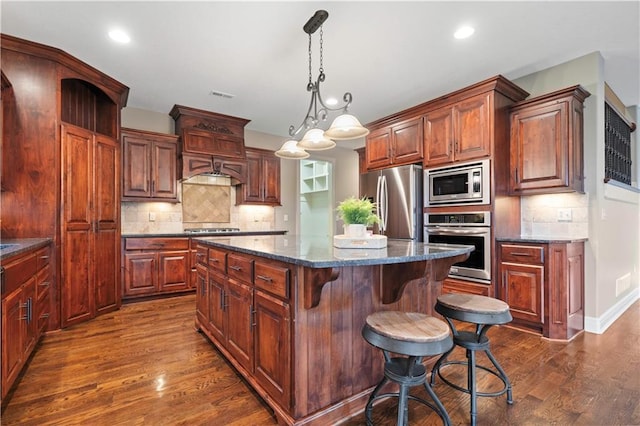 kitchen featuring a center island, appliances with stainless steel finishes, decorative backsplash, and dark wood-type flooring