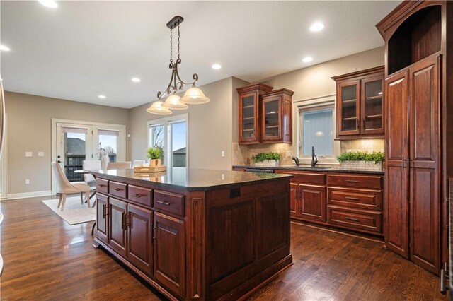 kitchen featuring a center island, dark wood-style floors, a sink, and decorative backsplash