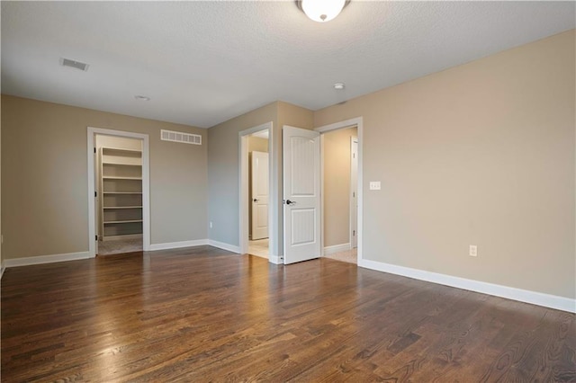 spare room featuring baseboards, visible vents, and wood finished floors