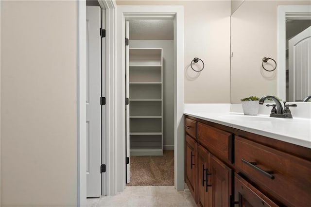 bathroom with a walk in closet, tile patterned flooring, and vanity