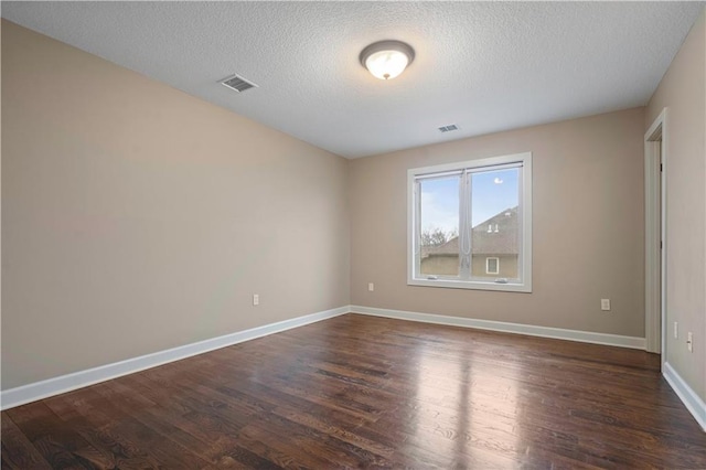 empty room with baseboards, visible vents, and dark wood-style flooring