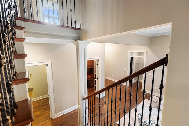 stairway featuring crown molding, wood finished floors, and baseboards