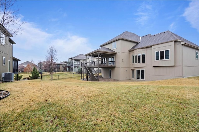 back of property with a shingled roof, central AC unit, a yard, and stairs