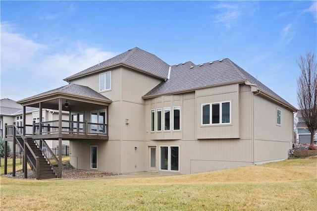 back of house with stairway, ceiling fan, a shingled roof, a wooden deck, and a lawn