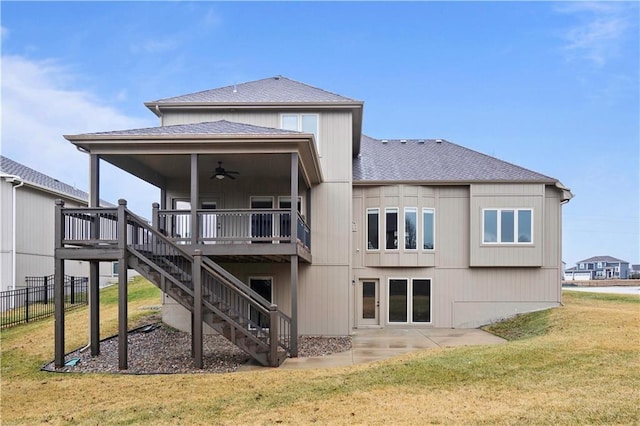 rear view of house featuring stairway, a shingled roof, a wooden deck, a ceiling fan, and a lawn
