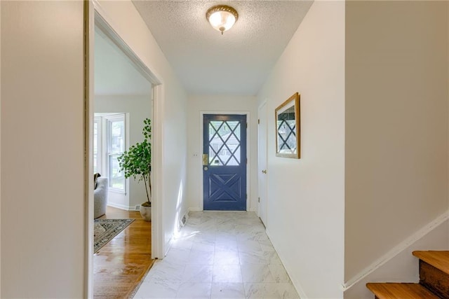 4401 E 104th St, Kansas City, MO 64137 - foyer entrance featuring plenty of natural light, light marble finish floors, a textured ceiling, baseboards, and stairs