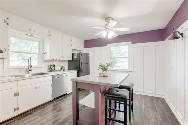 4401 E 104th St, Kansas City, MO 64137 - kitchen featuring stainless steel dishwasher, a sink, ceiling fan, light countertops, and healthy amount of natural light