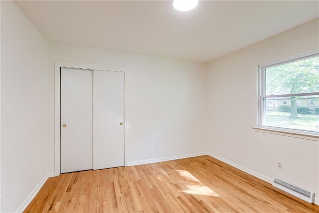 4401 E 104th St, Kansas City, MO 64137 - unfurnished bedroom with baseboard heating, light wood finished floors, baseboards, and a closet