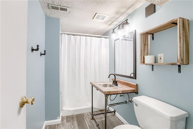 4401 E 104th St, Kansas City, MO 64137 - full bath featuring toilet, a textured ceiling, a shower with shower curtain, wood finished floors, and a sink