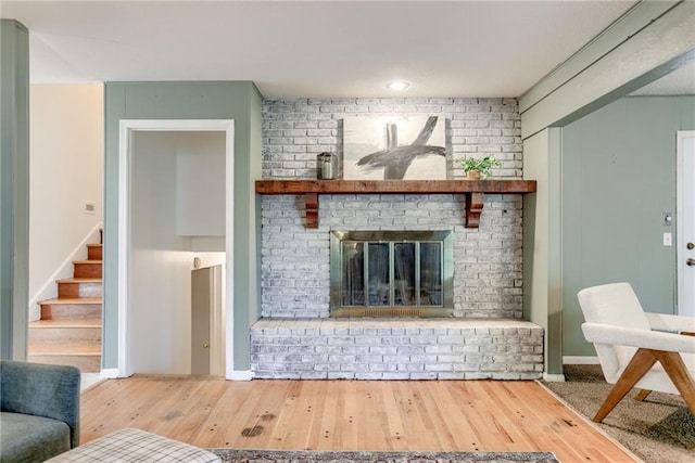 4401 E 104th St, Kansas City, MO 64137 - living room featuring wood finished floors, stairs, and a brick fireplace