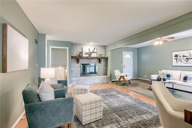 4401 E 104th St, Kansas City, MO 64137 - living area featuring wood finished floors, a brick fireplace, ceiling fan, and baseboards