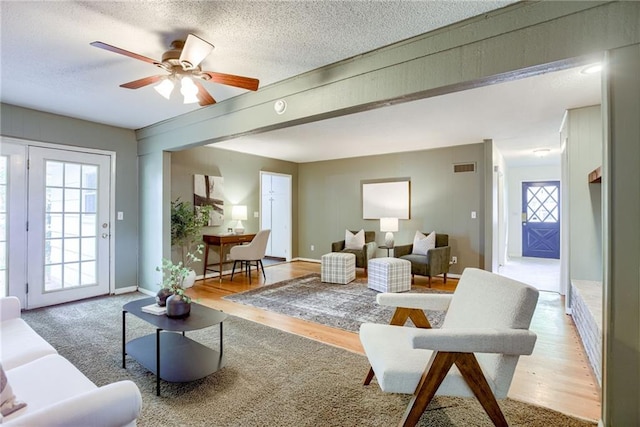 4401 E 104th St, Kansas City, MO 64137 - living room with healthy amount of natural light, a textured ceiling, wood finished floors, and ceiling fan