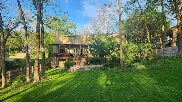 rear view of house featuring a chimney, a wooden deck, fence, a yard, and stairs
