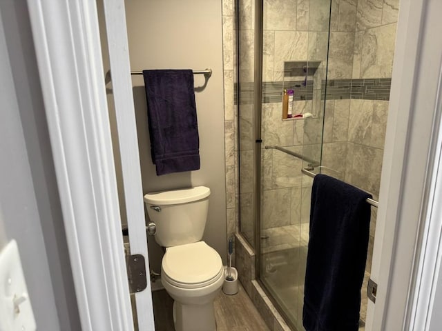 full bath with a shower stall, toilet, and wood finished floors