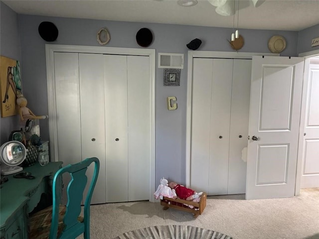 carpeted bedroom featuring visible vents and multiple closets