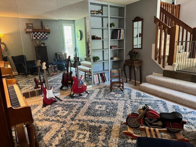 living area with baseboards, stairs, and a textured ceiling