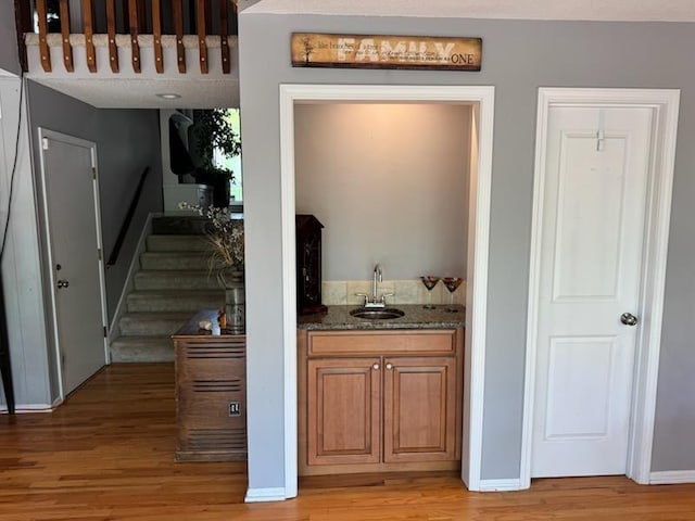 interior space featuring wet bar, a sink, stairway, and light wood-type flooring
