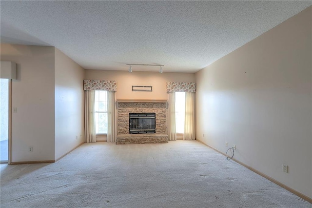 17800 E Bolger Rd Unit 245-A, Independence, MO 64055 - unfurnished living room with carpet, plenty of natural light, a textured ceiling, a stone fireplace, and baseboards