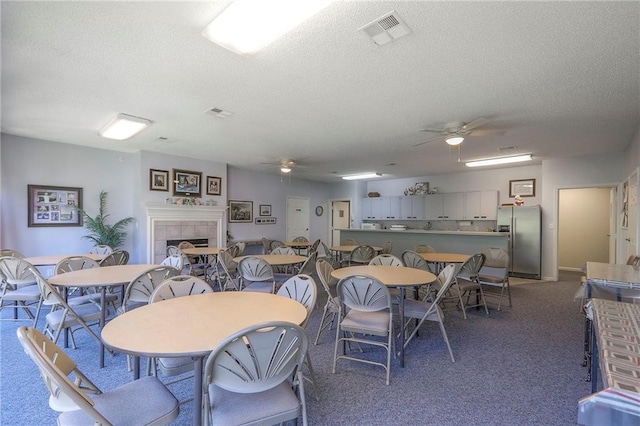 17800 E Bolger Rd Unit 245-A, Independence, MO 64055 - dining space featuring a ceiling fan, a textured ceiling, carpet floors, and a tile fireplace