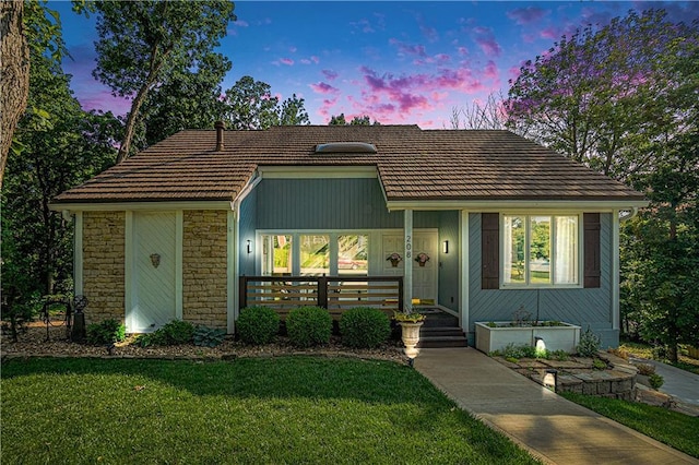 208 NE Landings Cir, Lees Summit, MO 64064 - view of front of home featuring a porch, a lawn, stone siding, and a tiled roof