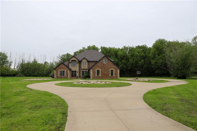 view of front of property with curved driveway, a front lawn, and brick siding