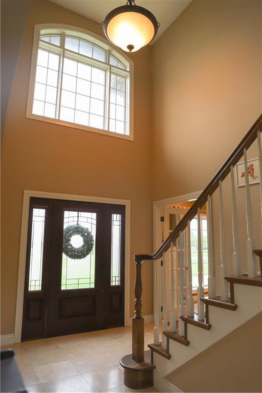 foyer featuring stairs, high vaulted ceiling, baseboards, and tile patterned floors