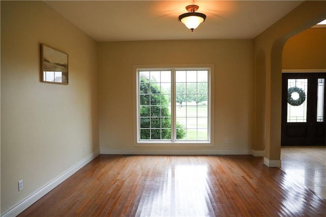 foyer entrance featuring arched walkways, baseboards, ornate columns, and hardwood / wood-style floors