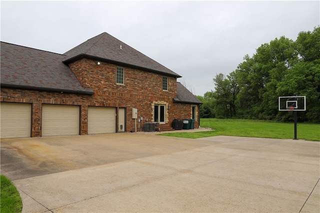 view of side of property with brick siding, central AC unit, a yard, and driveway