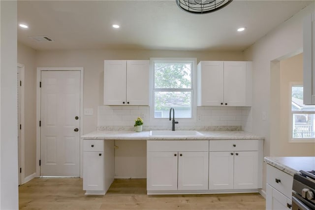 812 S Saville St, Independence, MO 64050 - kitchen with a sink, light wood-style floors, white cabinets, tasteful backsplash, and recessed lighting