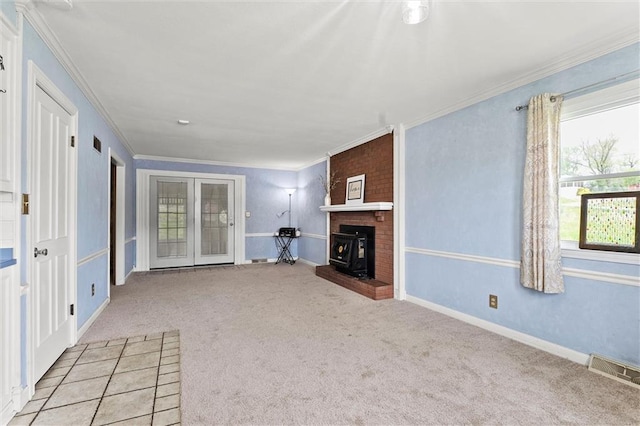 unfurnished living room featuring light colored carpet, crown molding, visible vents, a wood stove, and baseboards