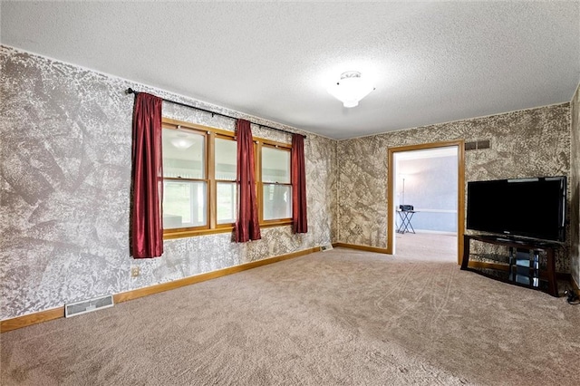 unfurnished living room featuring baseboards, carpet flooring, a textured ceiling, and visible vents