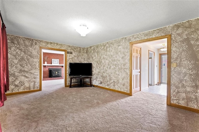 unfurnished living room featuring carpet floors, a brick fireplace, wallpapered walls, and a textured ceiling