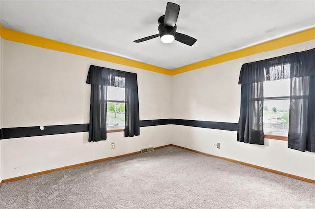 carpeted spare room with baseboards, ceiling fan, and visible vents