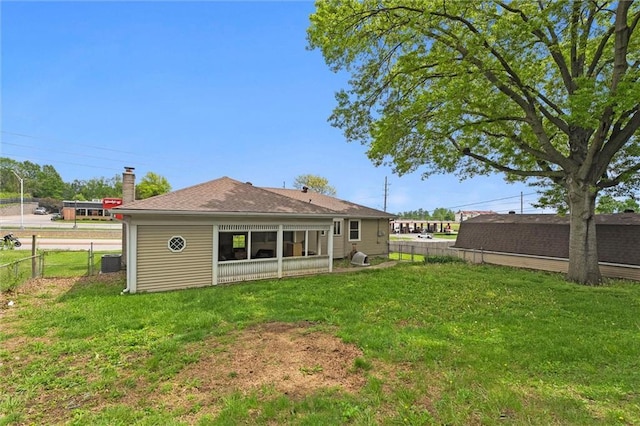 back of house featuring a fenced backyard, a shingled roof, and a yard