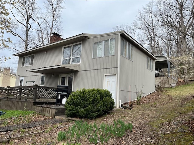 back of house with a chimney and a wooden deck