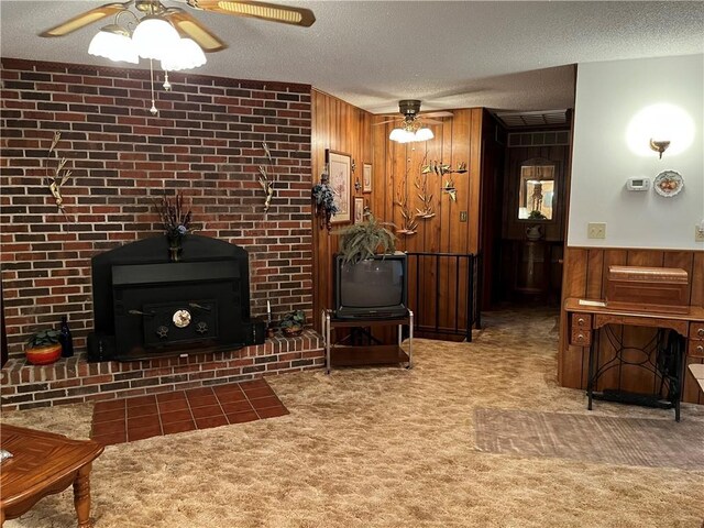 living area featuring wood walls, wainscoting, a textured ceiling, a ceiling fan, and carpet
