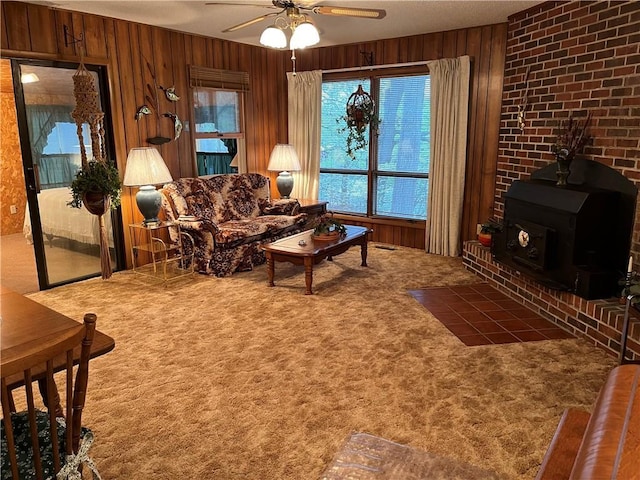 living area with wooden walls, ceiling fan, carpet flooring, and plenty of natural light