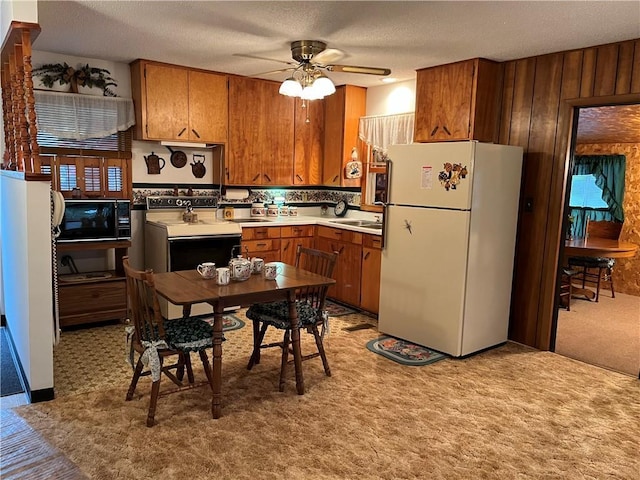 kitchen with freestanding refrigerator, black microwave, brown cabinetry, and range with electric stovetop