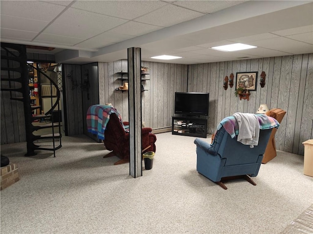 carpeted living area featuring stairs, wood walls, a paneled ceiling, and a baseboard radiator