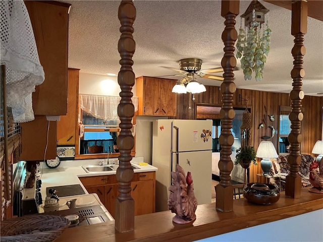 kitchen featuring freestanding refrigerator, a ceiling fan, brown cabinets, and light countertops
