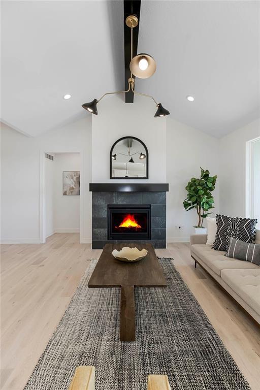 12541 S Hedge Ct, Olathe, KS 66061 - living room featuring lofted ceiling, wood finished floors, a tiled fireplace, baseboards, and recessed lighting