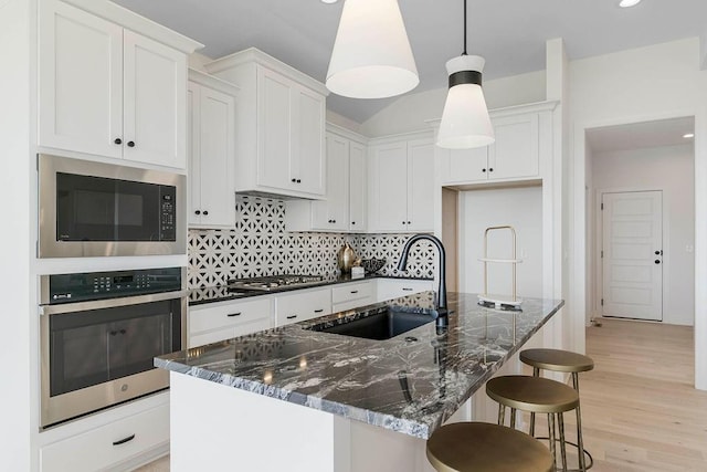 12541 S Hedge Ct, Olathe, KS 66061 - kitchen with appliances with stainless steel finishes, a sink, decorative backsplash, white cabinets, and a breakfast bar area