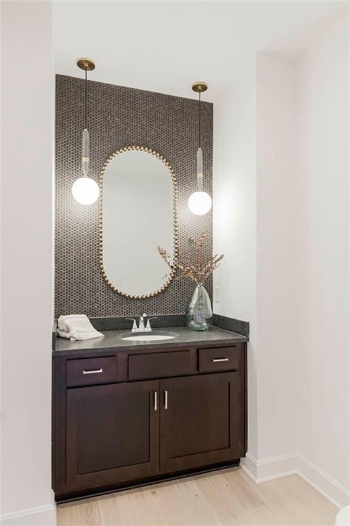 12541 S Hedge Ct, Olathe, KS 66061 - bar featuring a sink, baseboards, hanging light fixtures, and light wood-style flooring