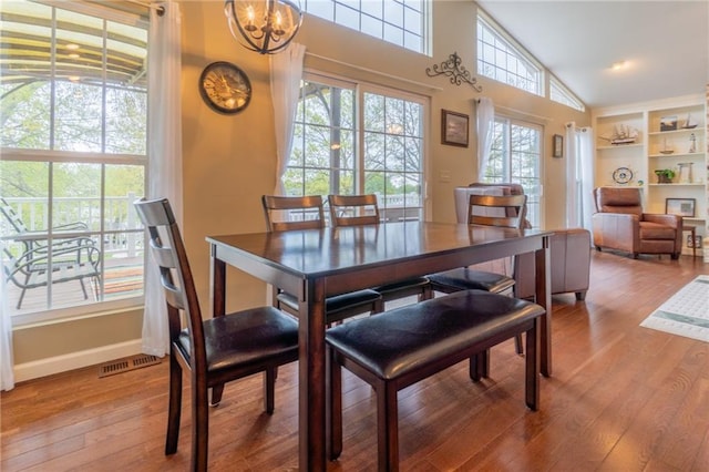 dining space featuring visible vents, baseboards, a notable chandelier, and hardwood / wood-style flooring