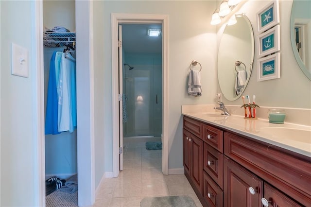 full bath featuring double vanity, a shower stall, a sink, tile patterned floors, and a spacious closet